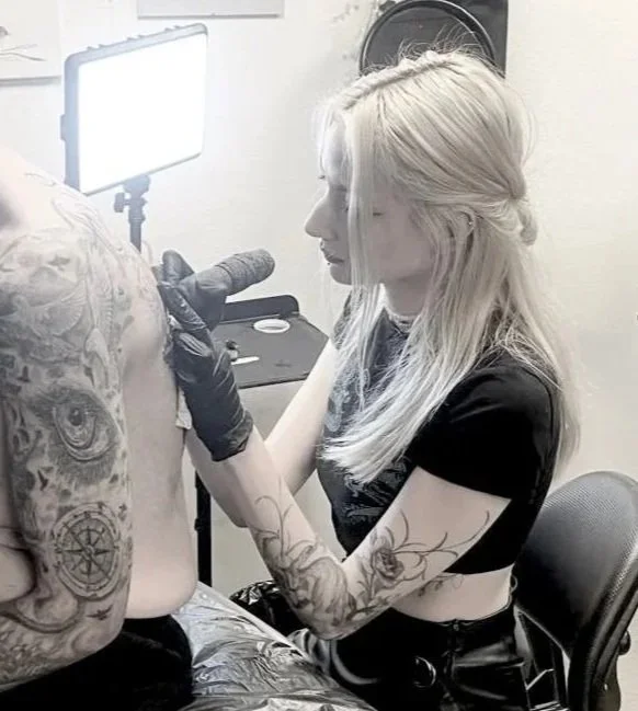 Tattoo artist tattooing client's back in private studio — dark illustrative and horror art on walls at Siren Tattoo Lucerne Switzerland