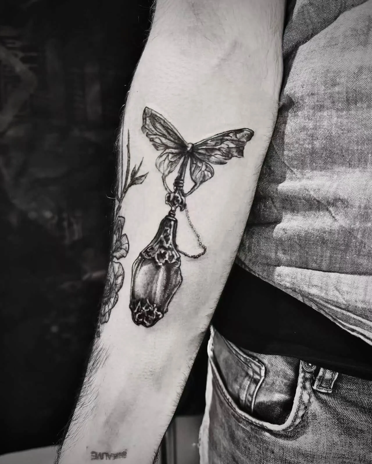 Fine-line butterfly and chrysalis tattoo on forearm — moth with hanging cocoon pendant and botanical detail by Siren Tattoo Lucerne
