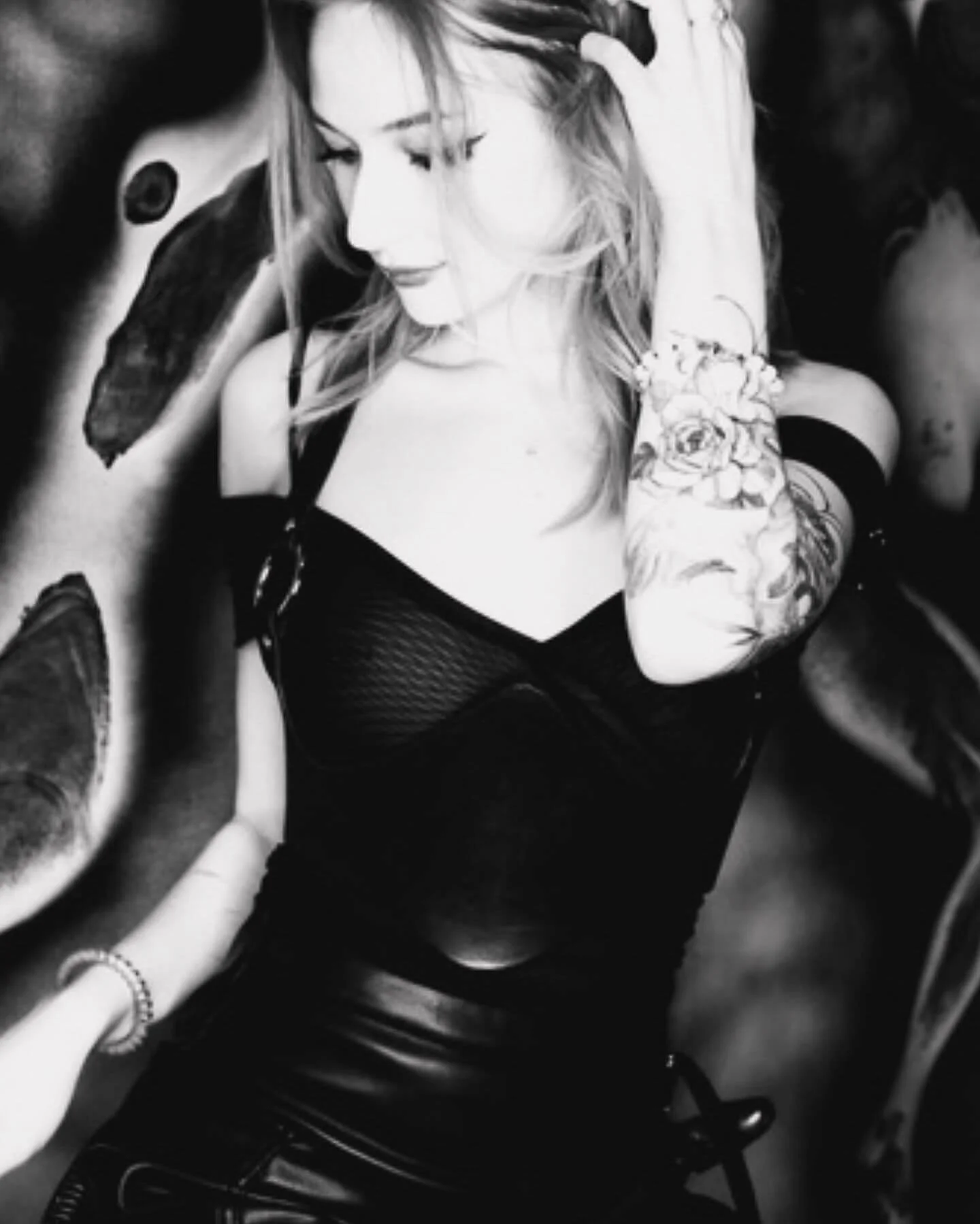 Portrait of Siren Tattoo artist in black and white — tattooed blonde woman in black corset surrounded by dark artwork at Siren Tattoo Lucerne