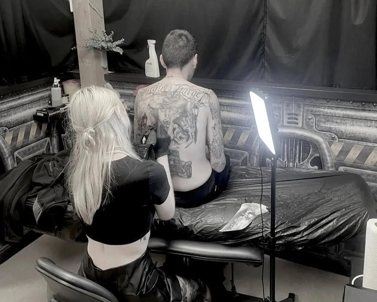 Tattoo artist working on full back piece in private studio — dark illustrative session at Siren Tattoo Lucerne Switzerland