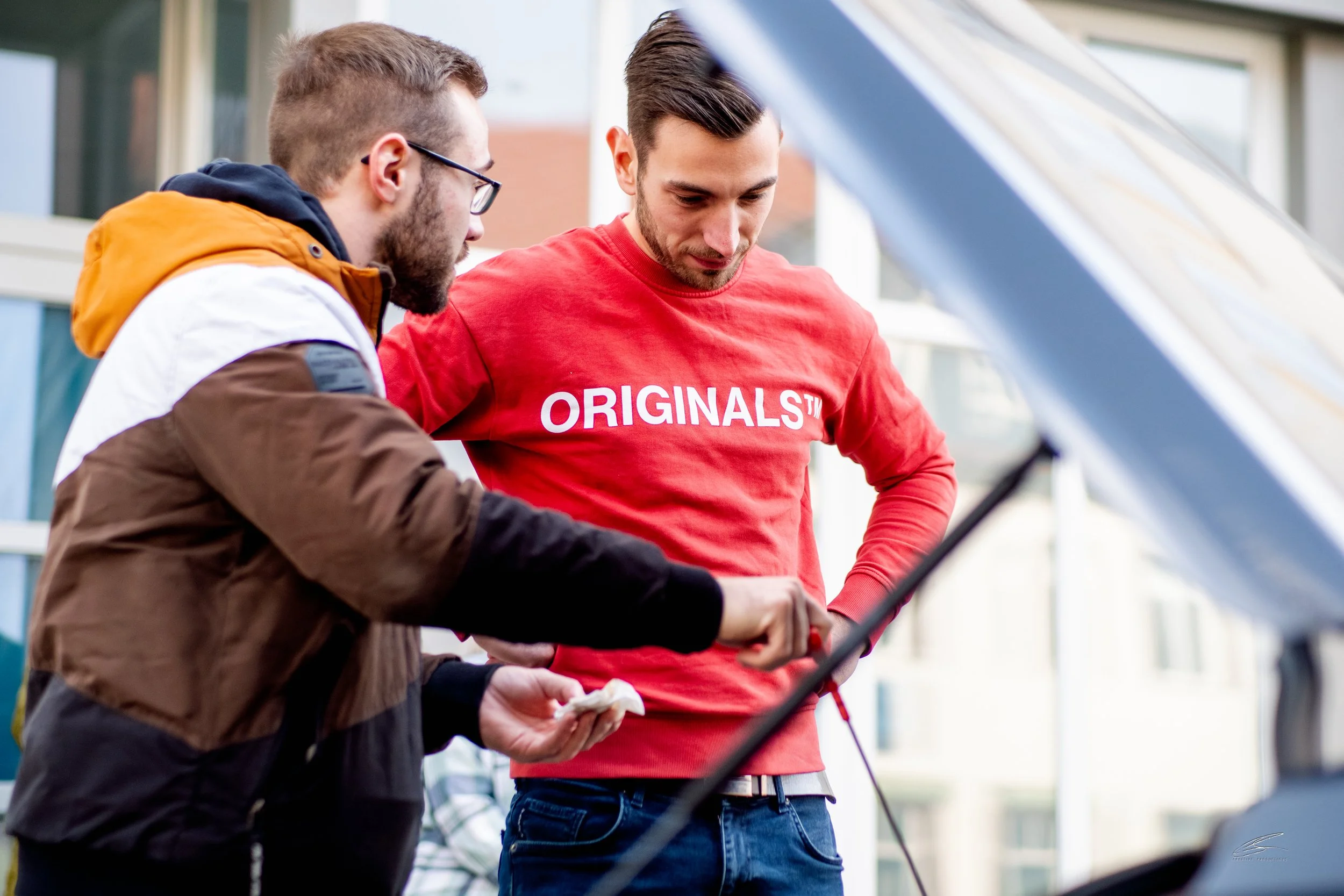 Zwei Männer schauen unter der Motorhaube eines Autos, während sie an einer Autoreparatur arbeiten.
