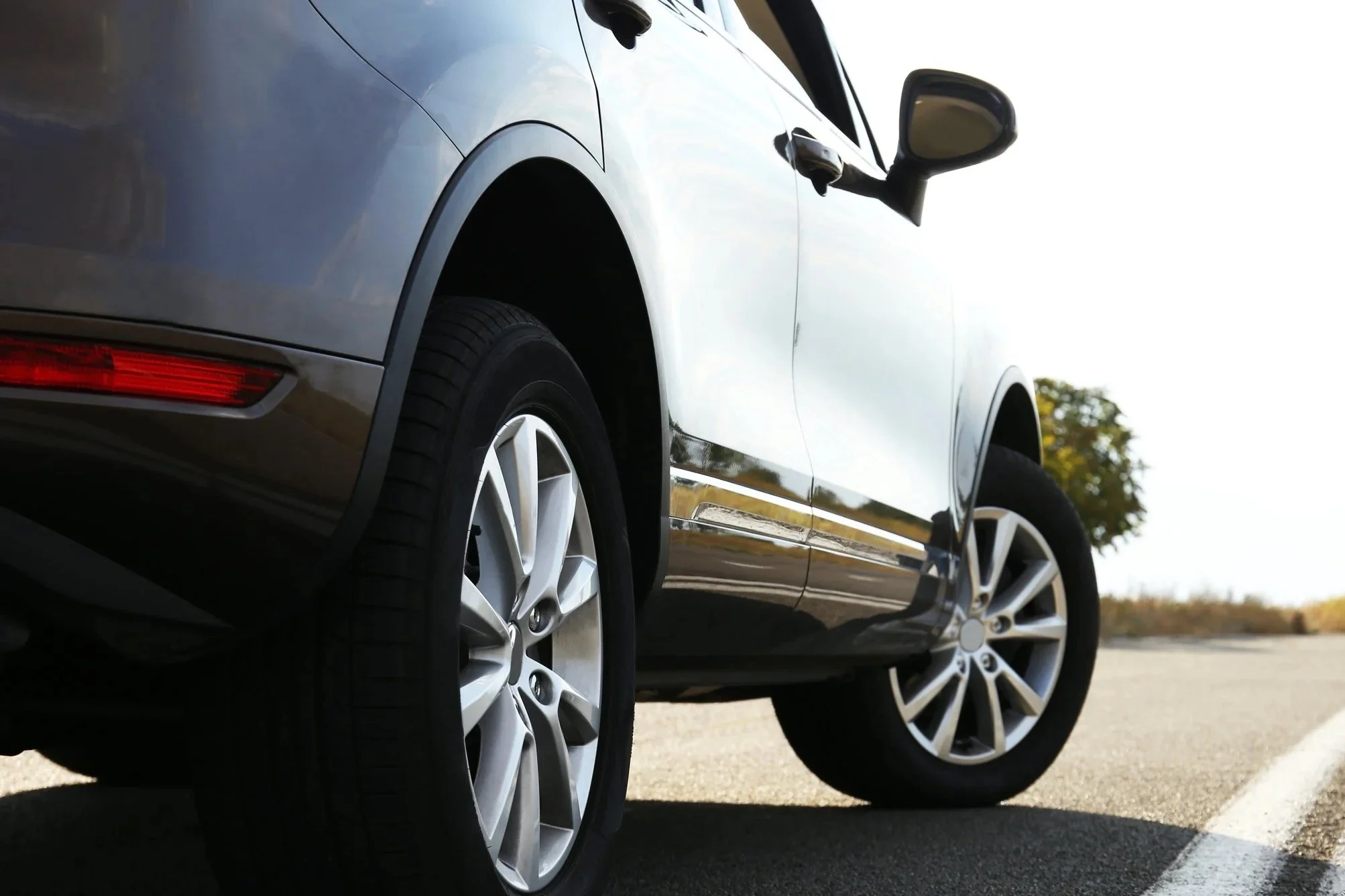 Ein schwarzes Auto steht auf einer Straße, Blick auf die linke Seite des Autos mit Blick auf die Vorderrad- und Hinterradfelgen.