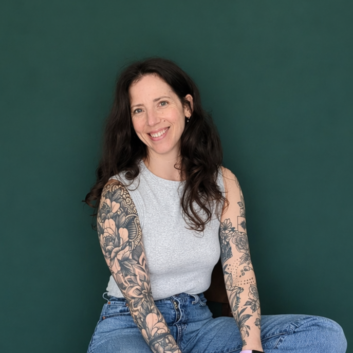 Headshot of smiling female tutor with long curly brown hair wearing a lanyard.