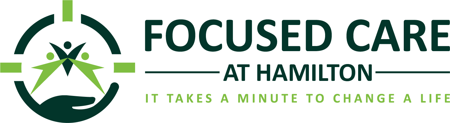 Logo of Focused Care at Hamilton with a graphic of three human figures in a circle, a hand supporting them, and a crosshair target around them, accompanied by the slogan "It takes a minute to change a life."