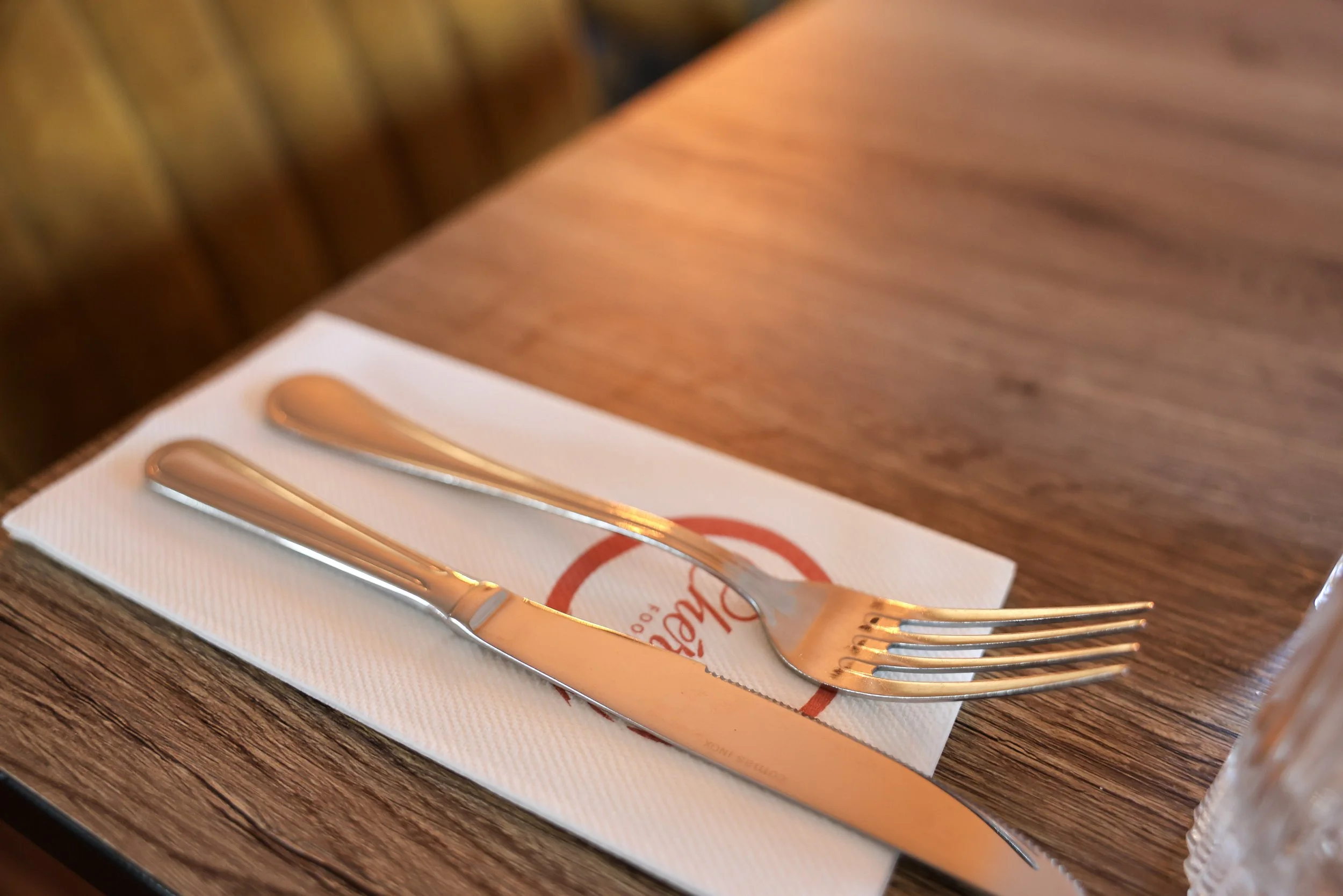 Vork en mes op een wit servet op een houten restauranttafel.