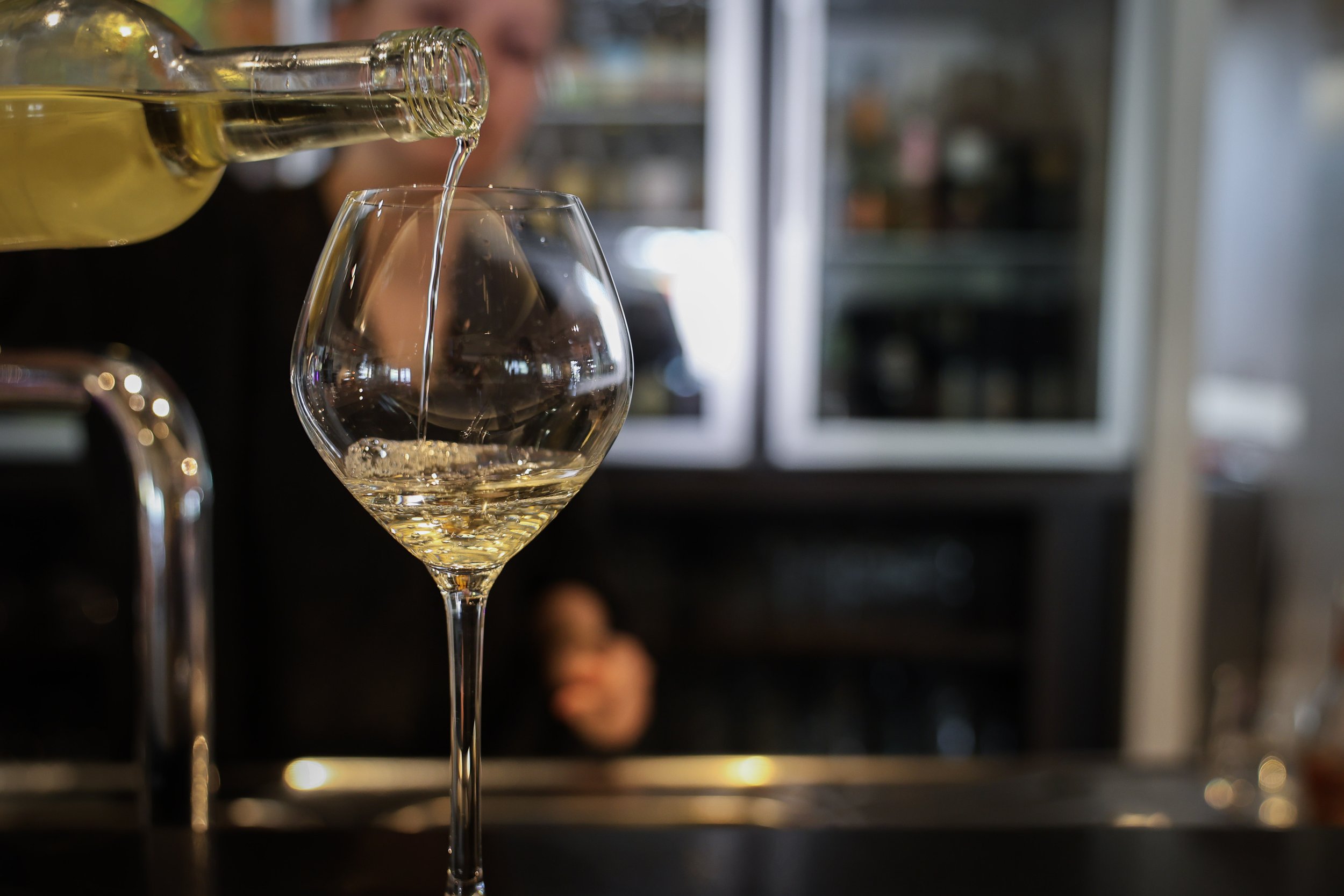 Witte wijn die wordt ingeschonken in een wijnglas aan een bar of in een restaurant.