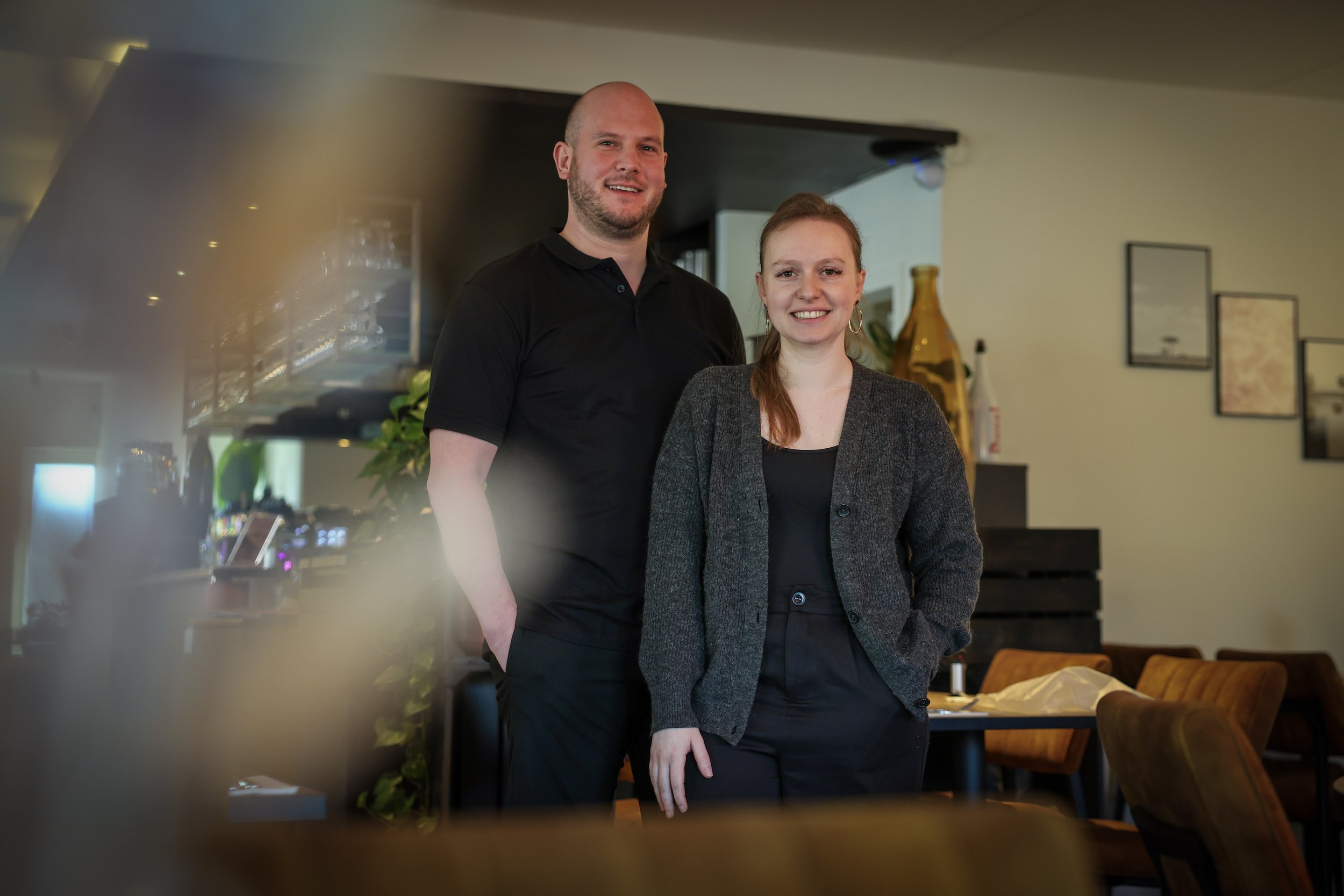 Man en vrouw die lachend in een restaurant poseren voor de camera.