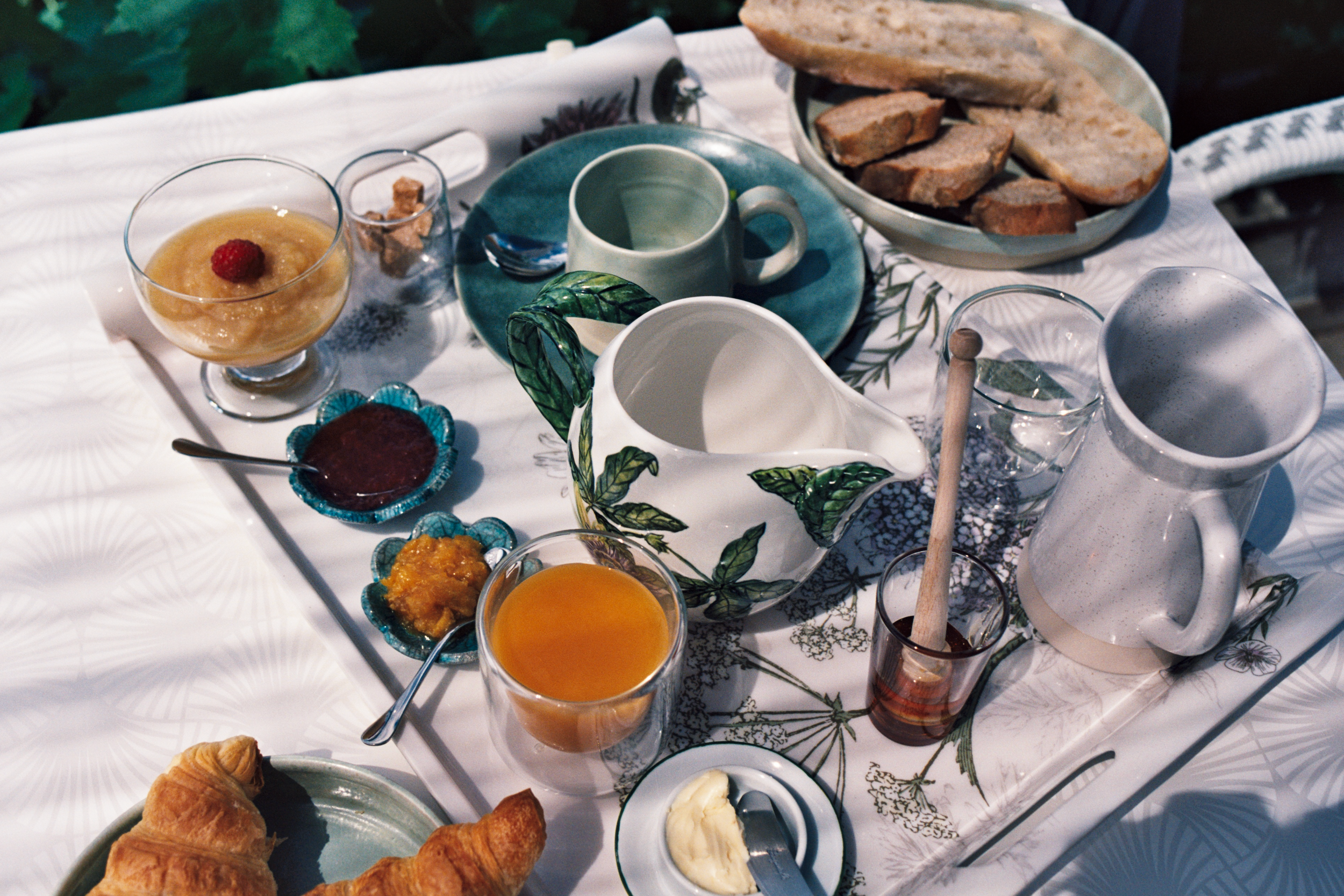 Plateau de petit déjeuner avec croissant, compote, jus d'orange, pain, confitures bio