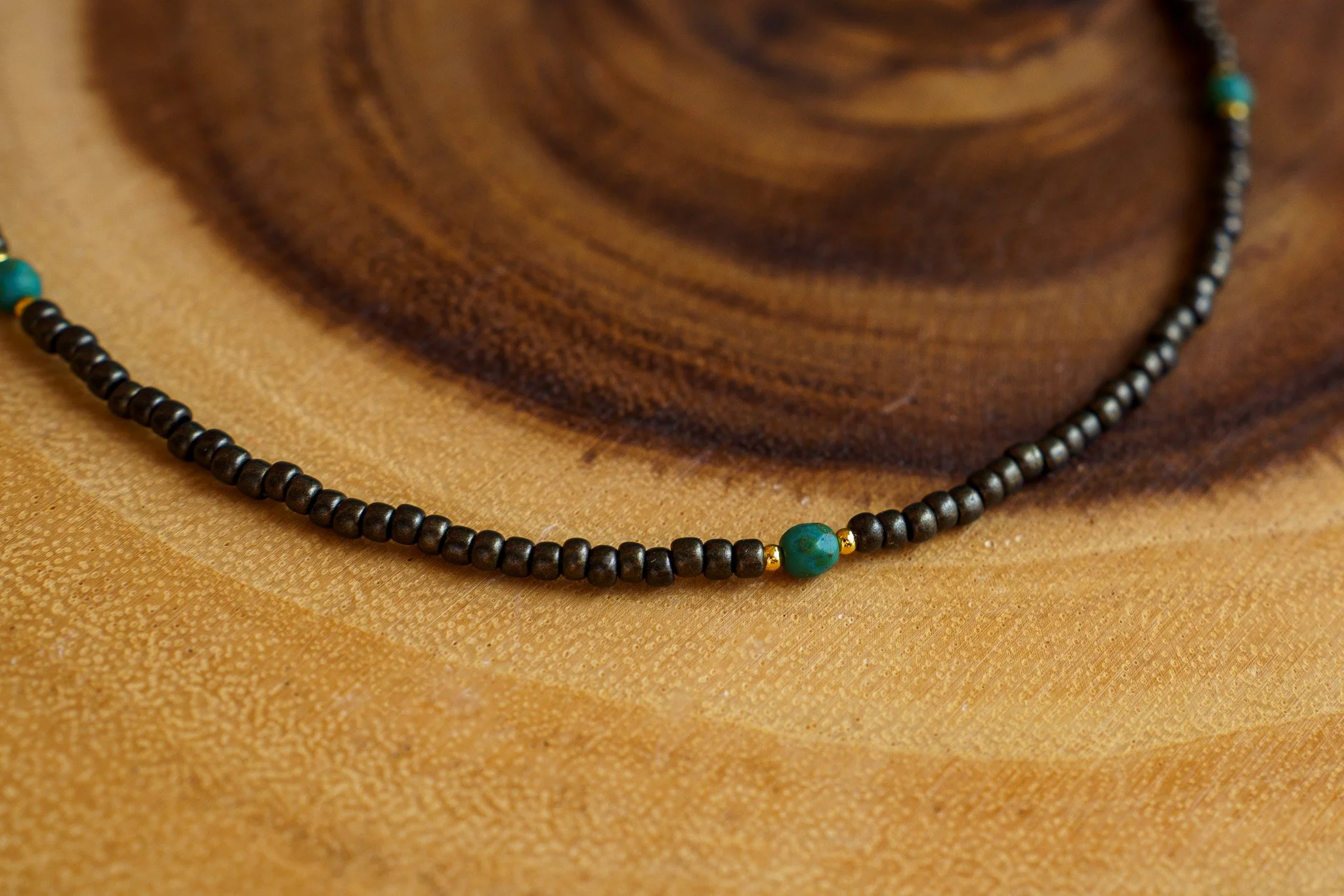 Handmade necklace with teal accent beads and black and gold seed beads with 18k gold PVD findings. Necklace measures approximately 17" with a 2" extender.