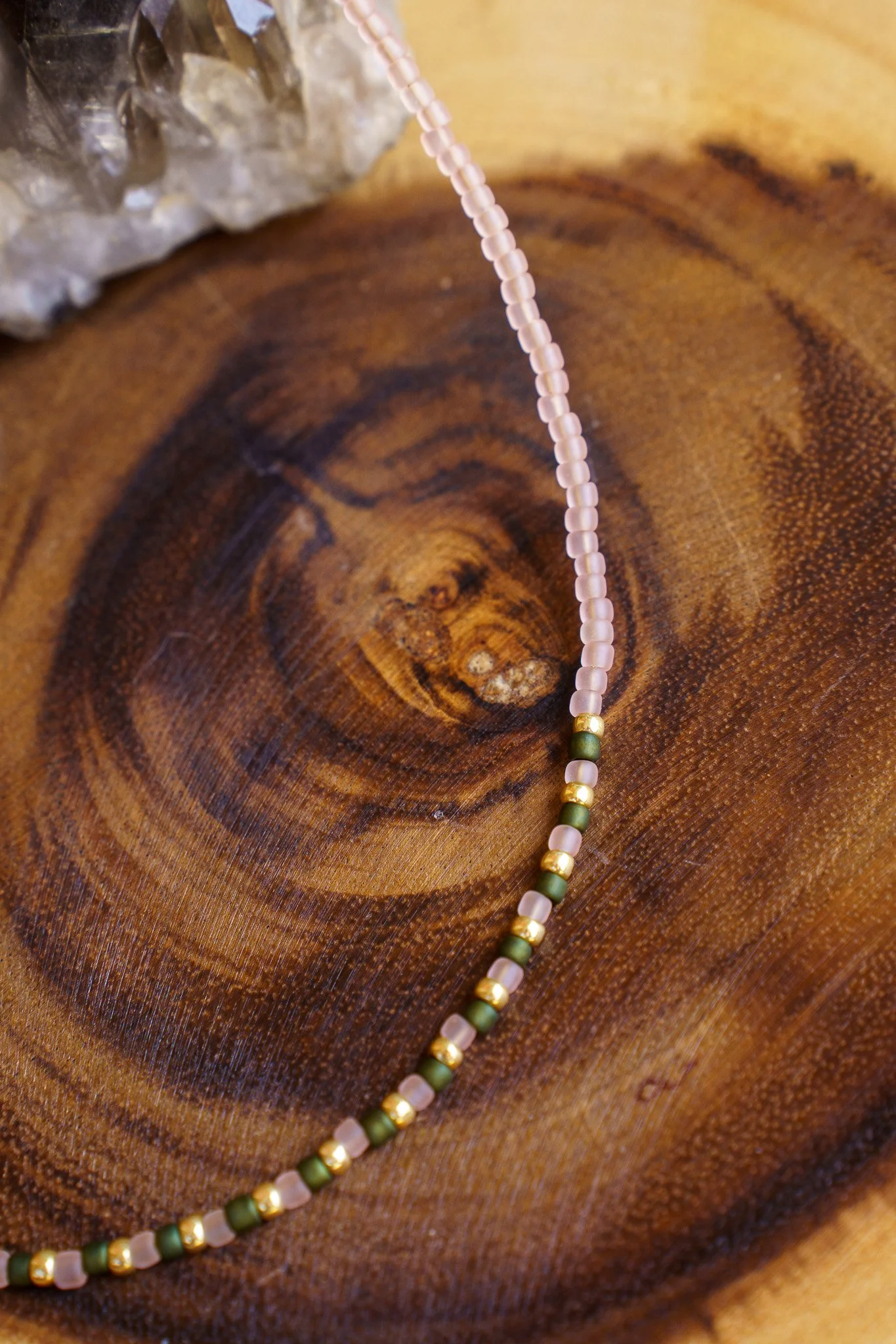 Handmade green, pink, and gold seed bead necklace with 18k gold PVD findings. Necklace measures approximately 16" with a 2" extender.
