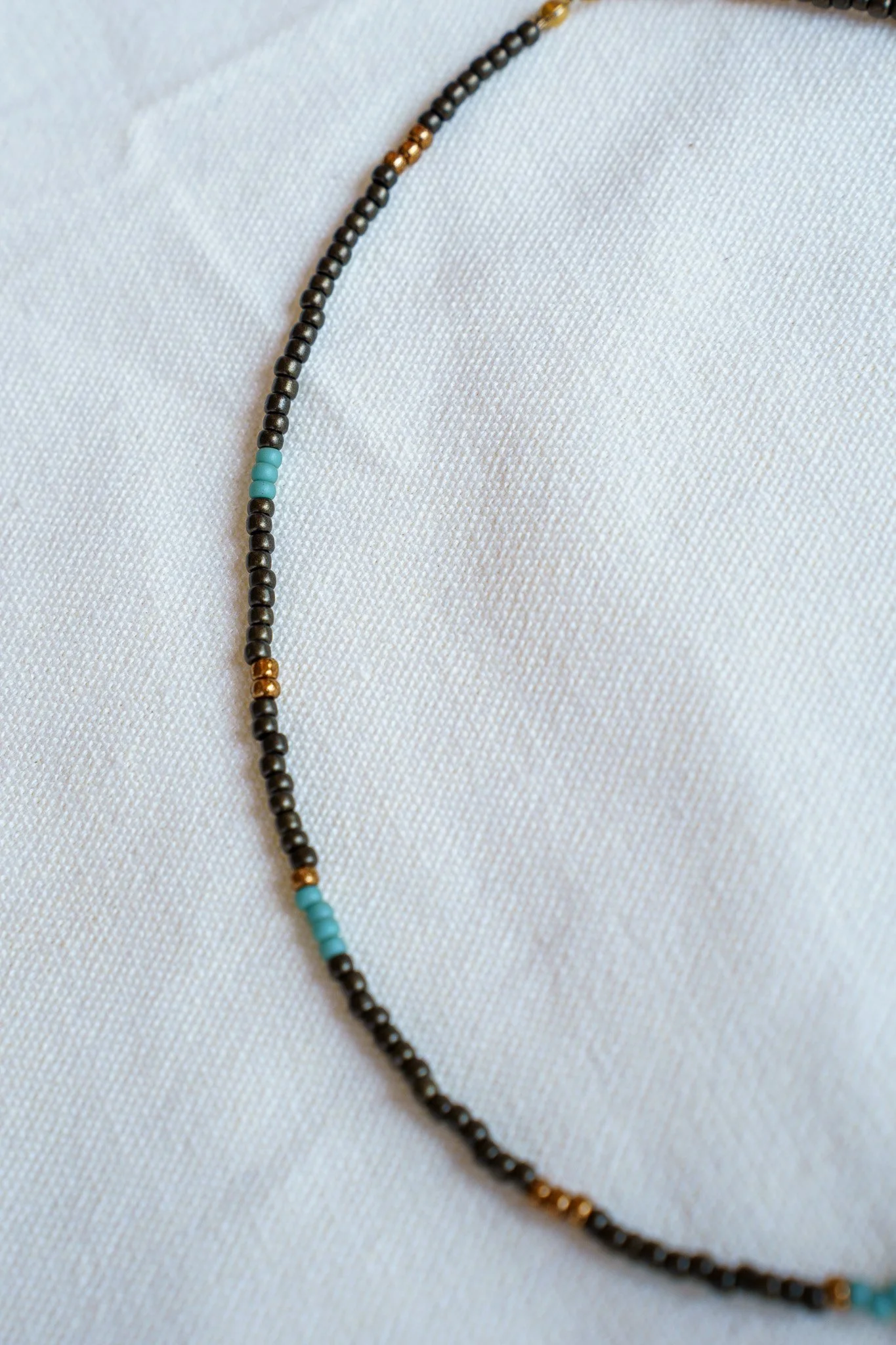 Handmade necklace with three kiwi jasper stones and black and bronze seed beads with 18k gold PVD findings. Necklace measures approximately 16" with a 2" extender.