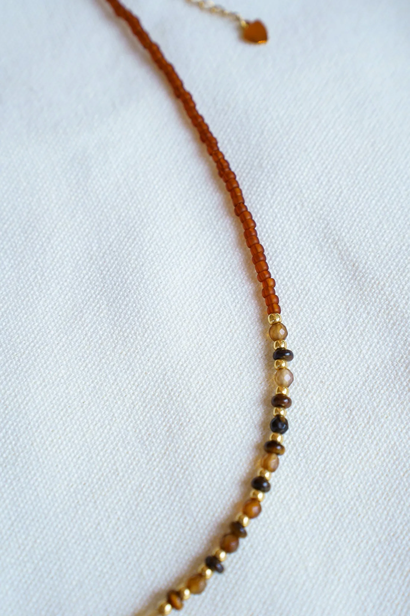 Handmade tiger’s eye stone necklace with rust brown and gold seed beads and 18k gold PVD findings. Necklace measures approximately 17" with a 2" extender.