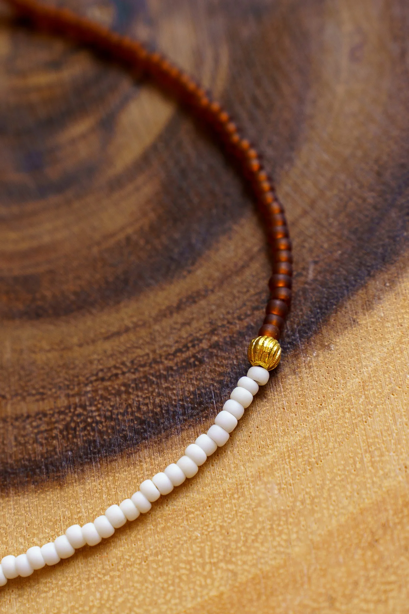 Handmade necklace with white, rust brown, and gold seed beads and with 18k gold PVD findings. Necklace measures approximately 16" with a 2" extender.
