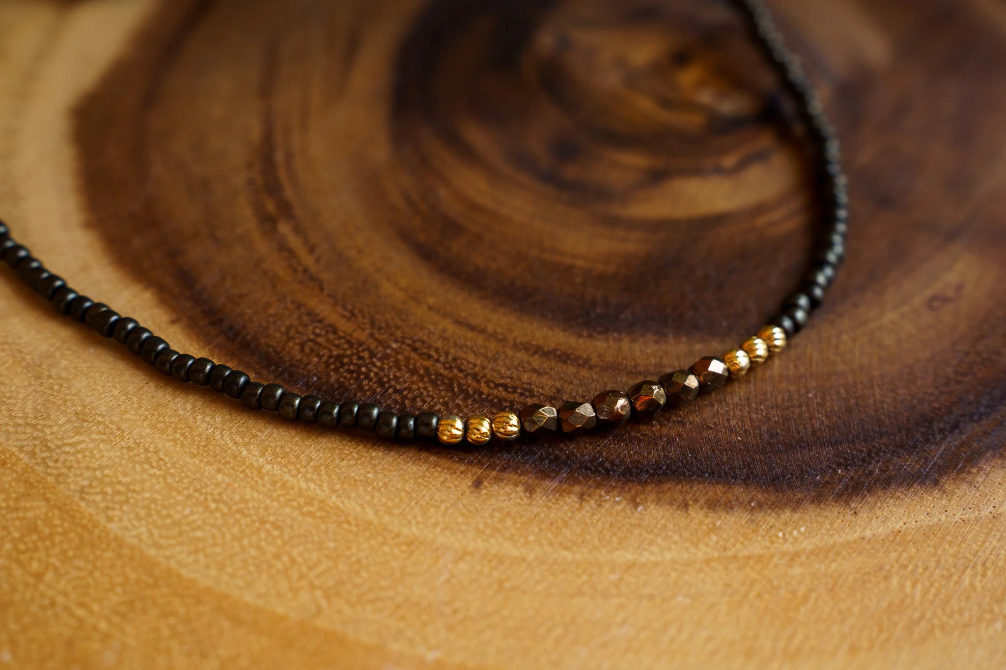 Handmade necklace with brown accent beads with black and gold seed beads and 18k gold PVD findings. Necklace measures approximately 15.5" with a 2" extender.