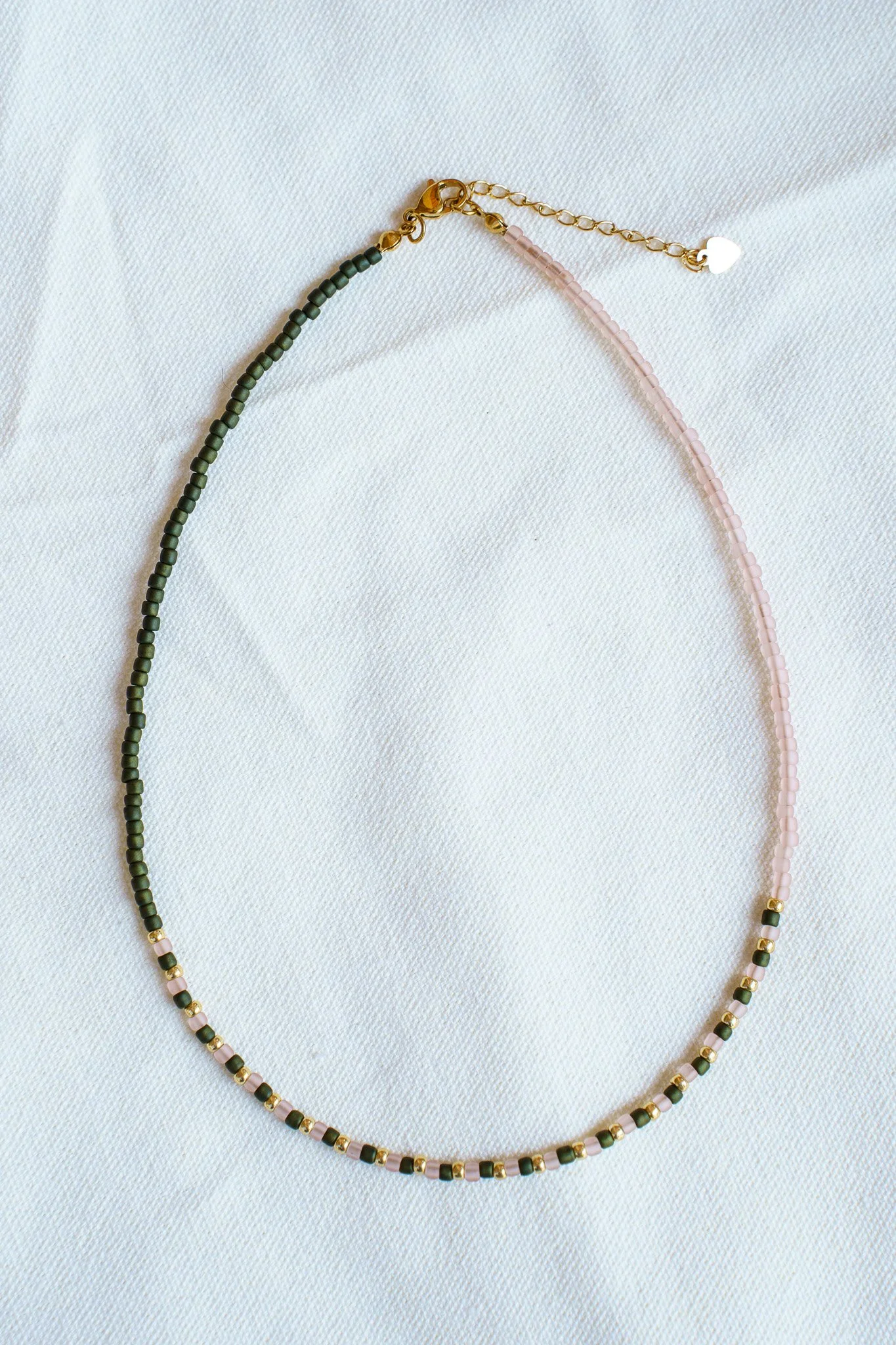 Handmade green, pink, and gold seed bead necklace with 18k gold PVD findings. Necklace measures approximately 16" with a 2" extender.
