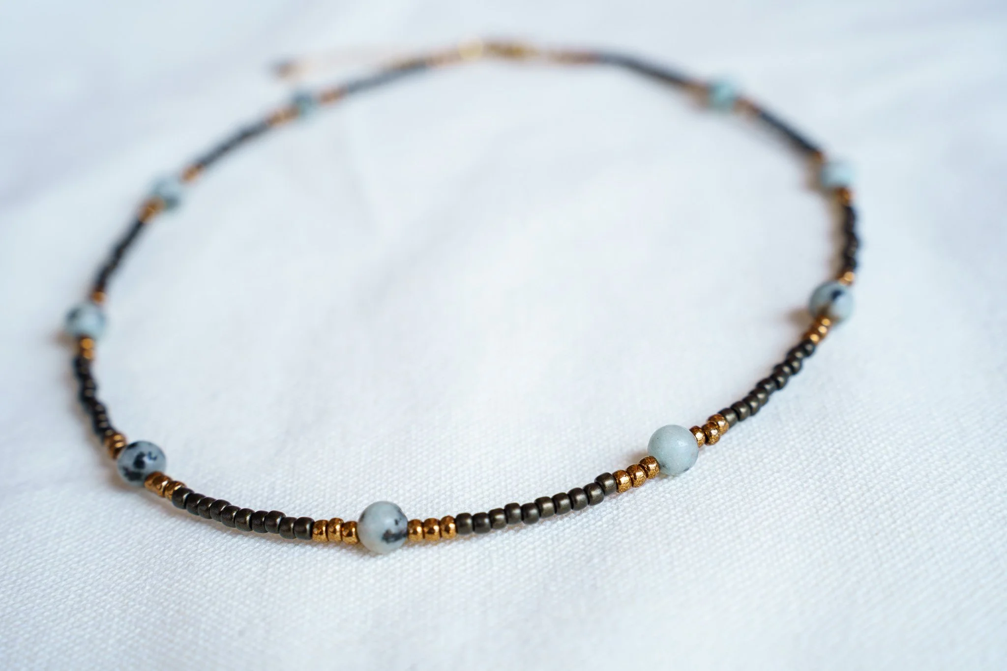 Handmade kiwi jasper necklace with black and bronze seed beads and 18k gold PVD findings. Necklace measures approximately 16" with a 2" extender.
