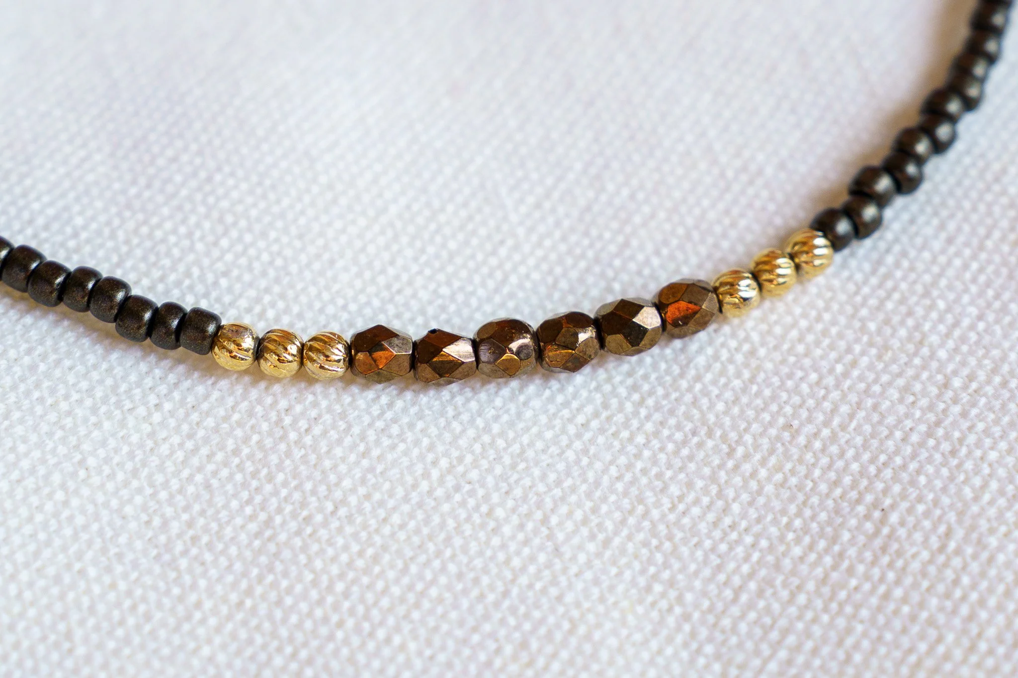 Handmade necklace with brown accent beads with black and gold seed beads and 18k gold PVD findings. Necklace measures approximately 15.5" with a 2" extender.
