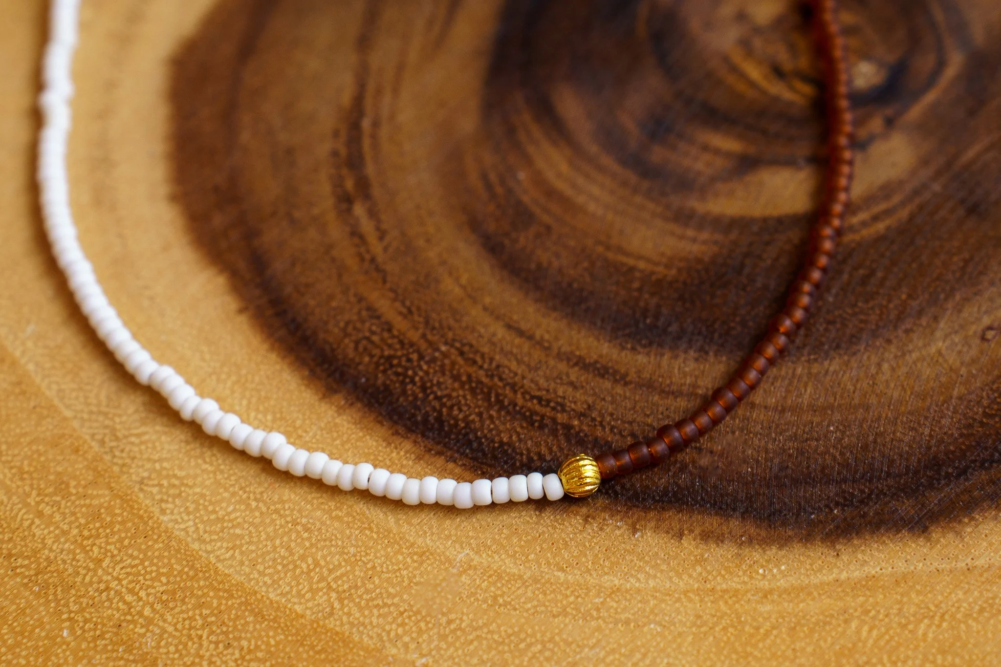 Handmade necklace with white, rust brown, and gold seed beads and with 18k gold PVD findings. Necklace measures approximately 16" with a 2" extender.
