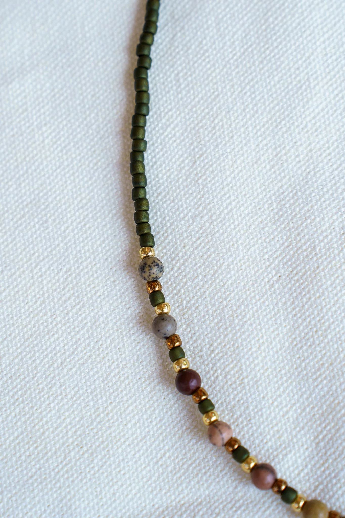 Handmade pink zebra jasper necklace with green and gold seed beads and 18k gold PVD findings. Necklace measures approximately 16" with a 2" extender.