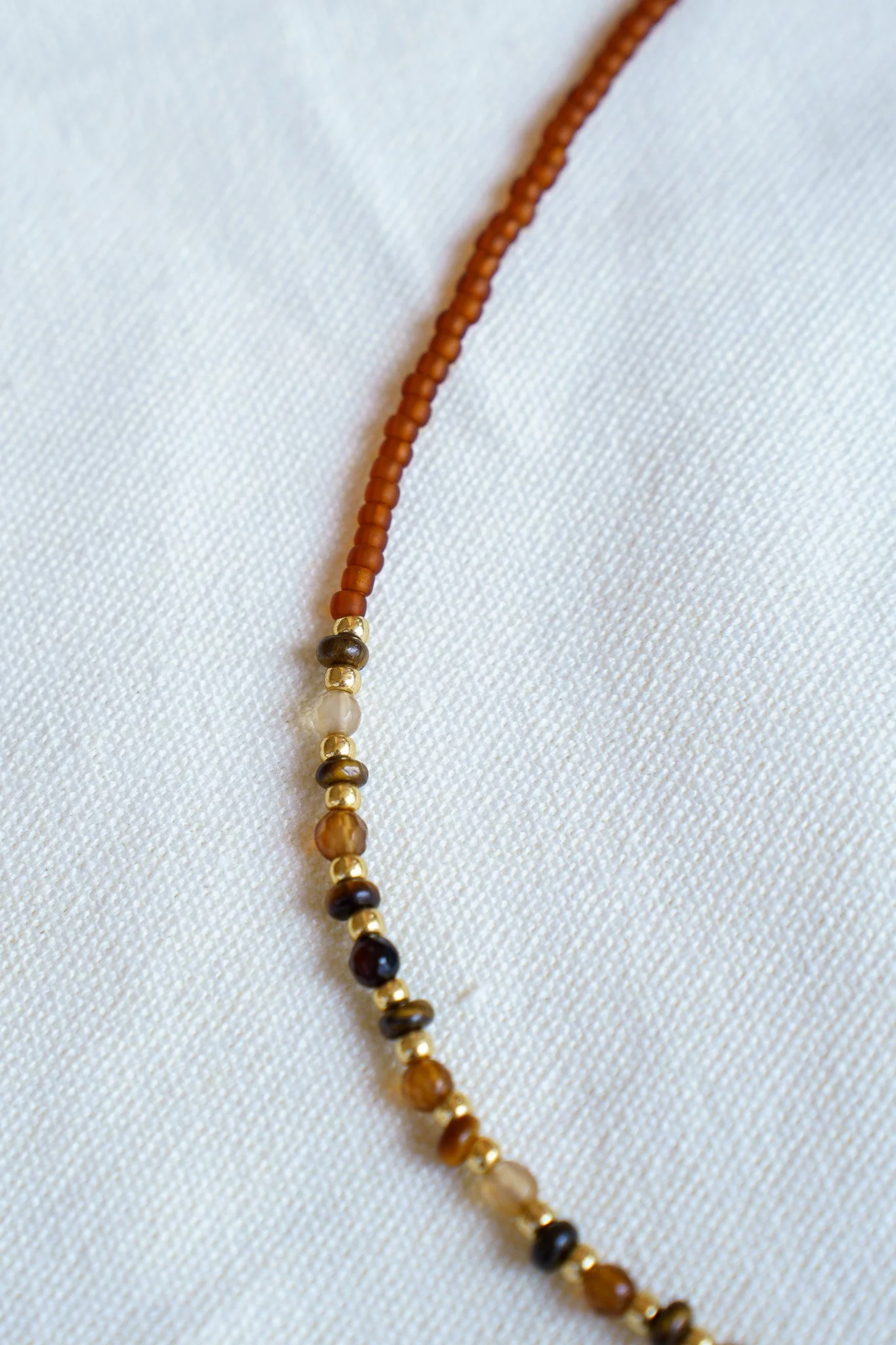 Handmade tiger’s eye stone necklace with rust brown and gold seed beads and 18k gold PVD findings. Necklace measures approximately 17" with a 2" extender.