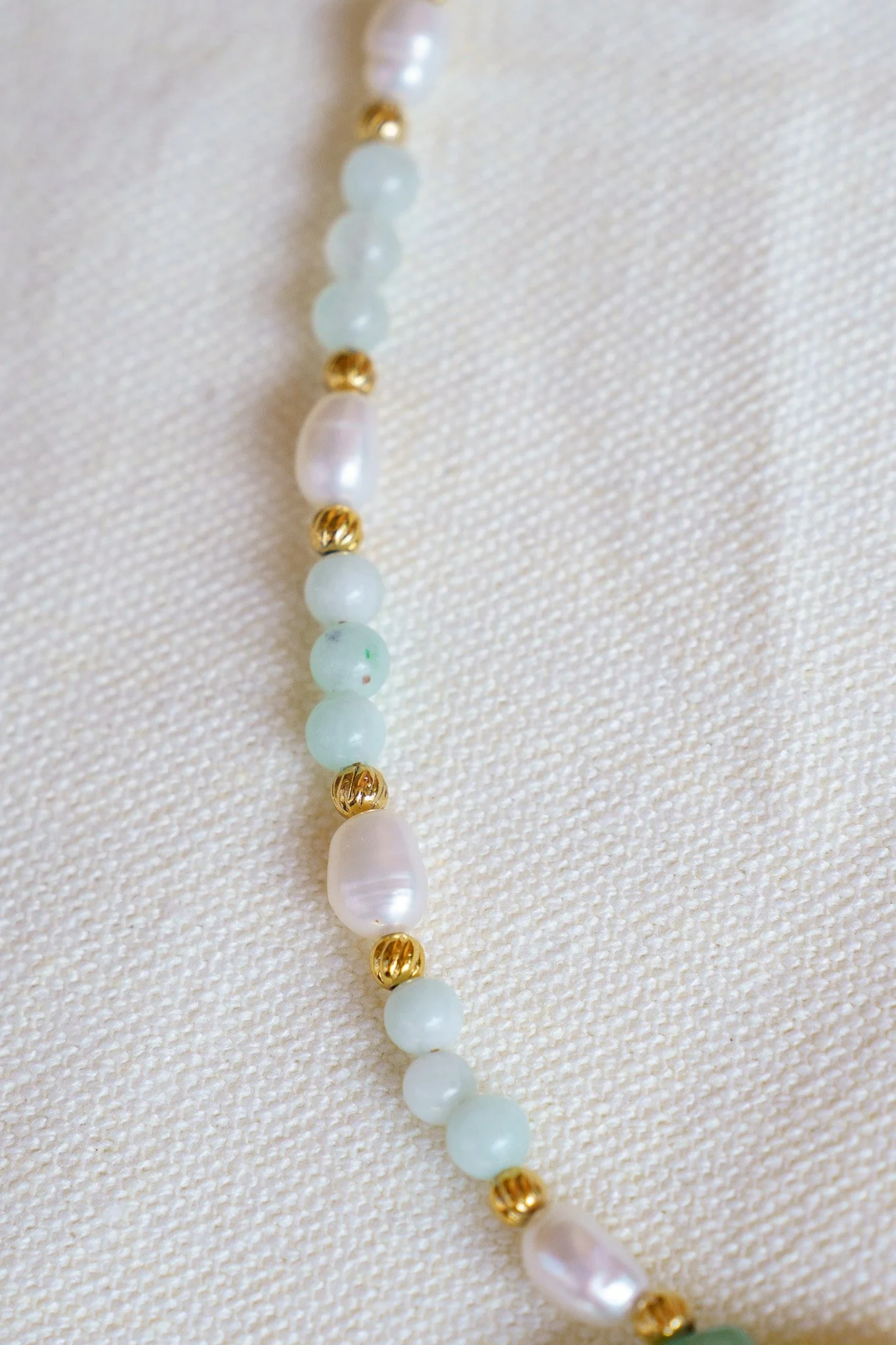 Handmade necklace with amazonite beads, freshwater pearls, and a green aventurine pendant with gold seed beads and 18k gold PVD findings. Necklace measures approximately 15" with a 2" extender.
