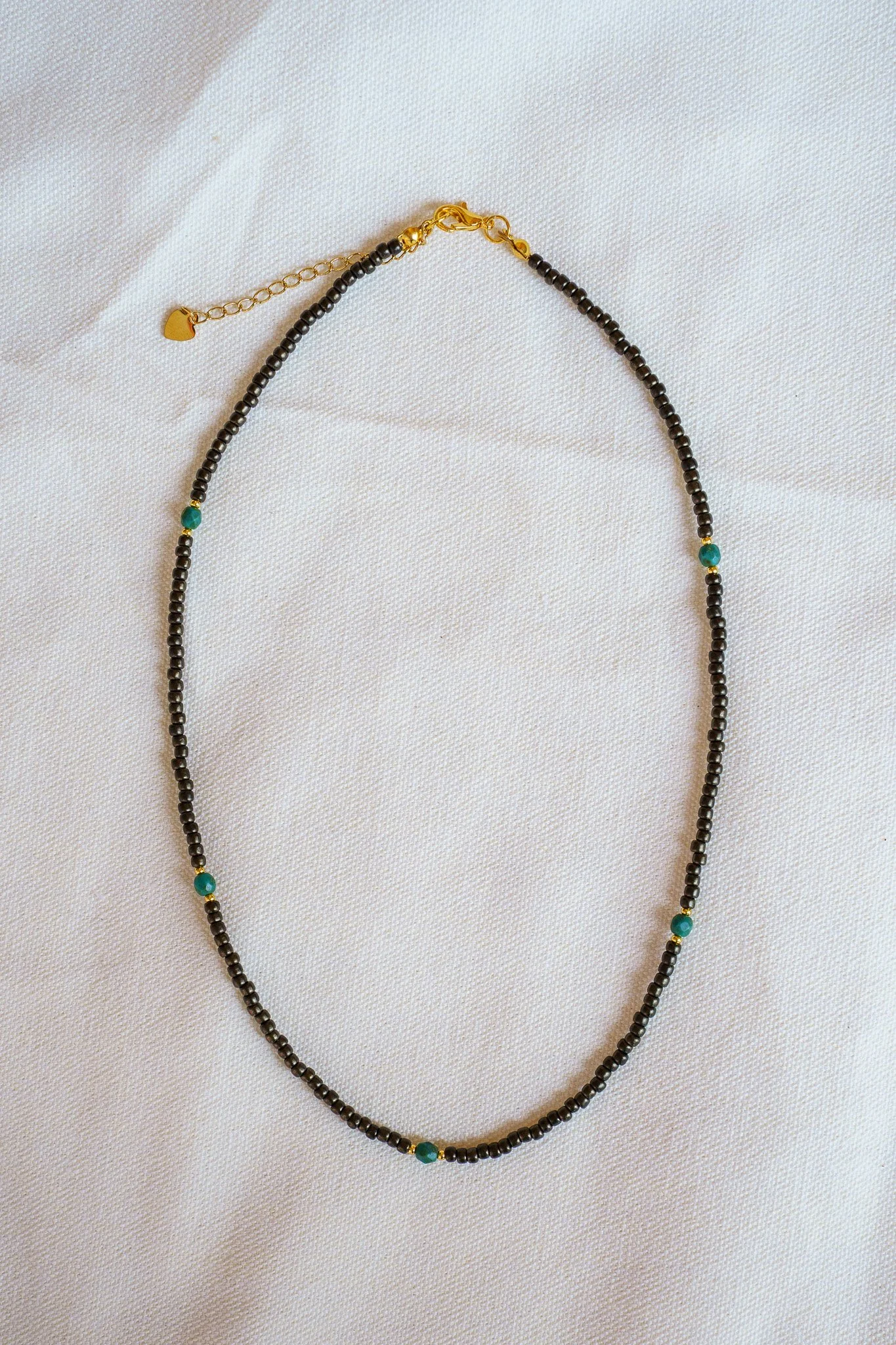 Handmade necklace with teal accent beads and black and gold seed beads with 18k gold PVD findings. Necklace measures approximately 17" with a 2" extender.