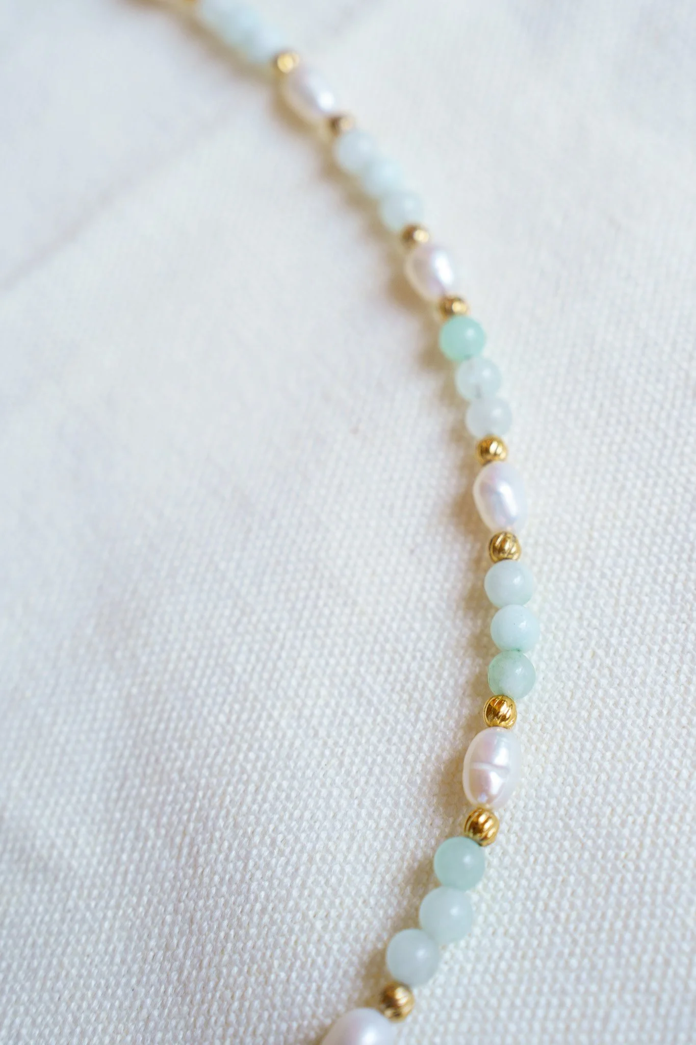 Handmade necklace with amazonite beads, freshwater pearls, and a green aventurine pendant with gold seed beads and 18k gold PVD findings. Necklace measures approximately 15" with a 2" extender.
