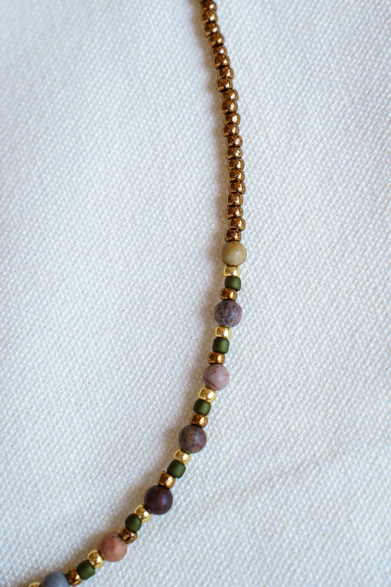 Handmade pink zebra jasper necklace with green and gold seed beads and 18k gold PVD findings. Necklace measures approximately 16" with a 2" extender.