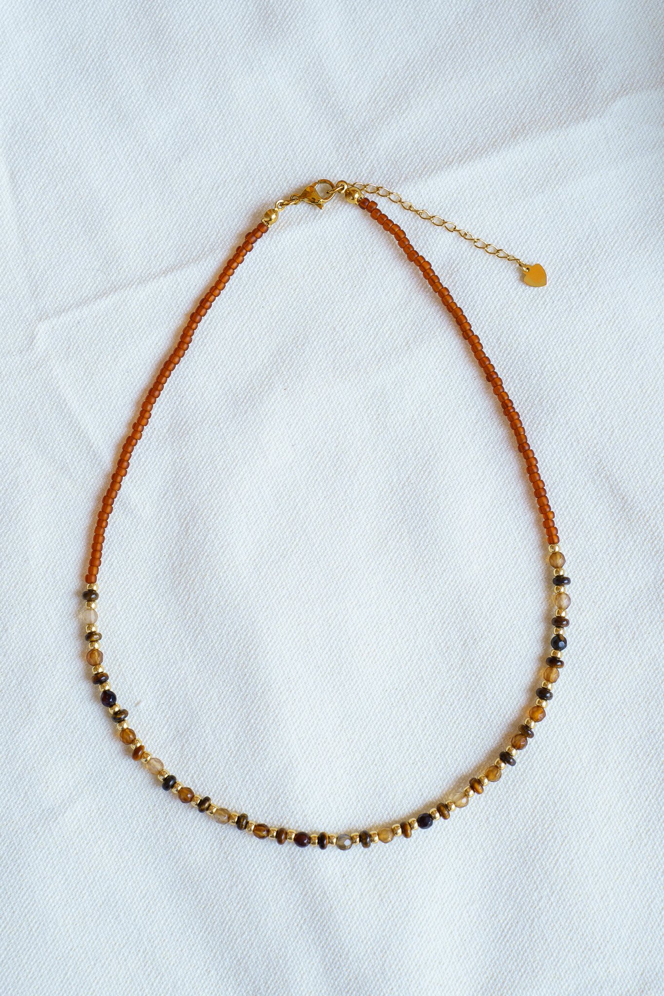 Handmade tiger’s eye stone necklace with rust brown and gold seed beads and 18k gold PVD findings. Necklace measures approximately 17" with a 2" extender.