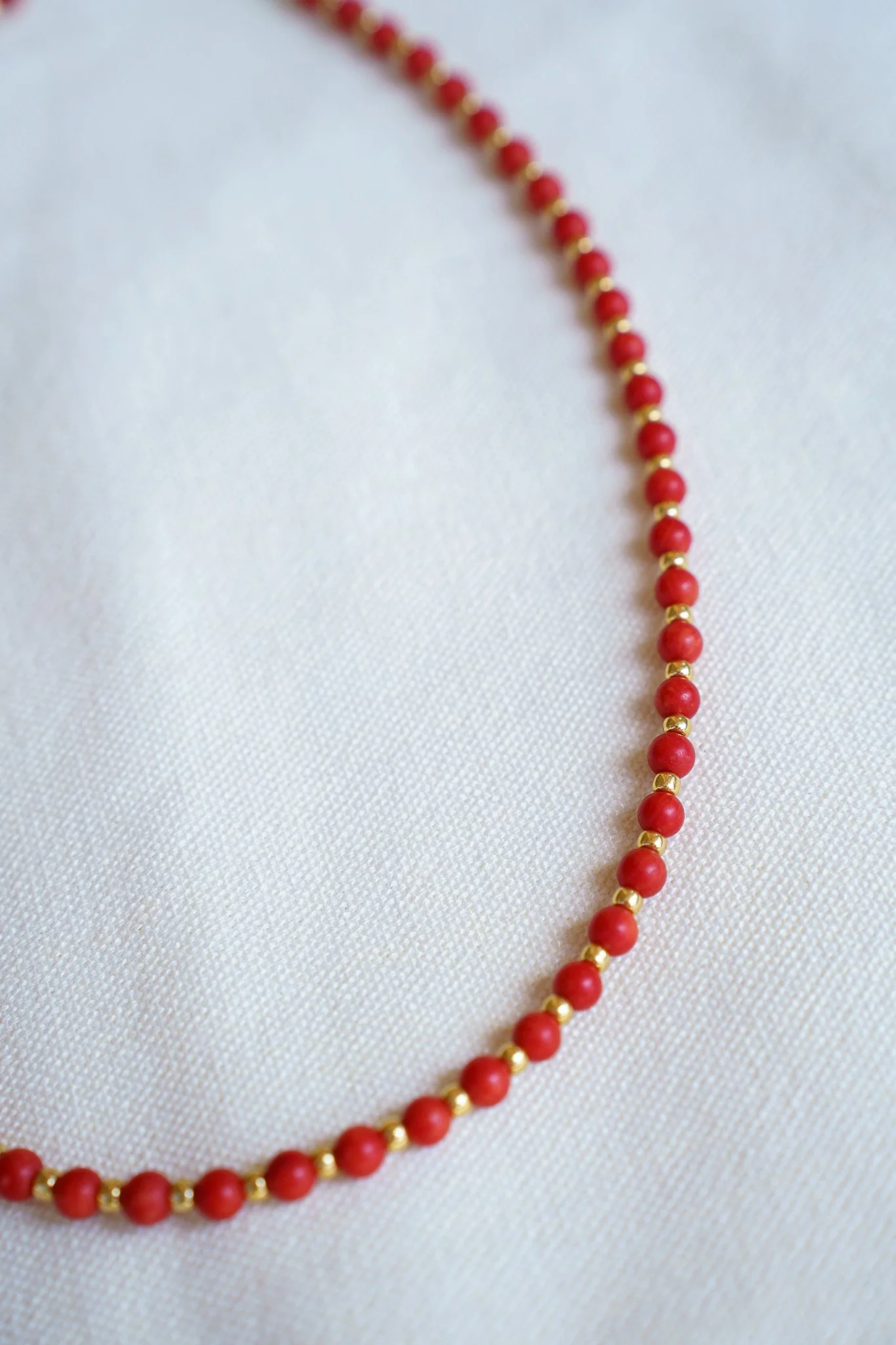 Handmade coral bead necklace with gold seed beads and 18k gold PVD findings. Necklace measures approximately 17" with a 2" extender.