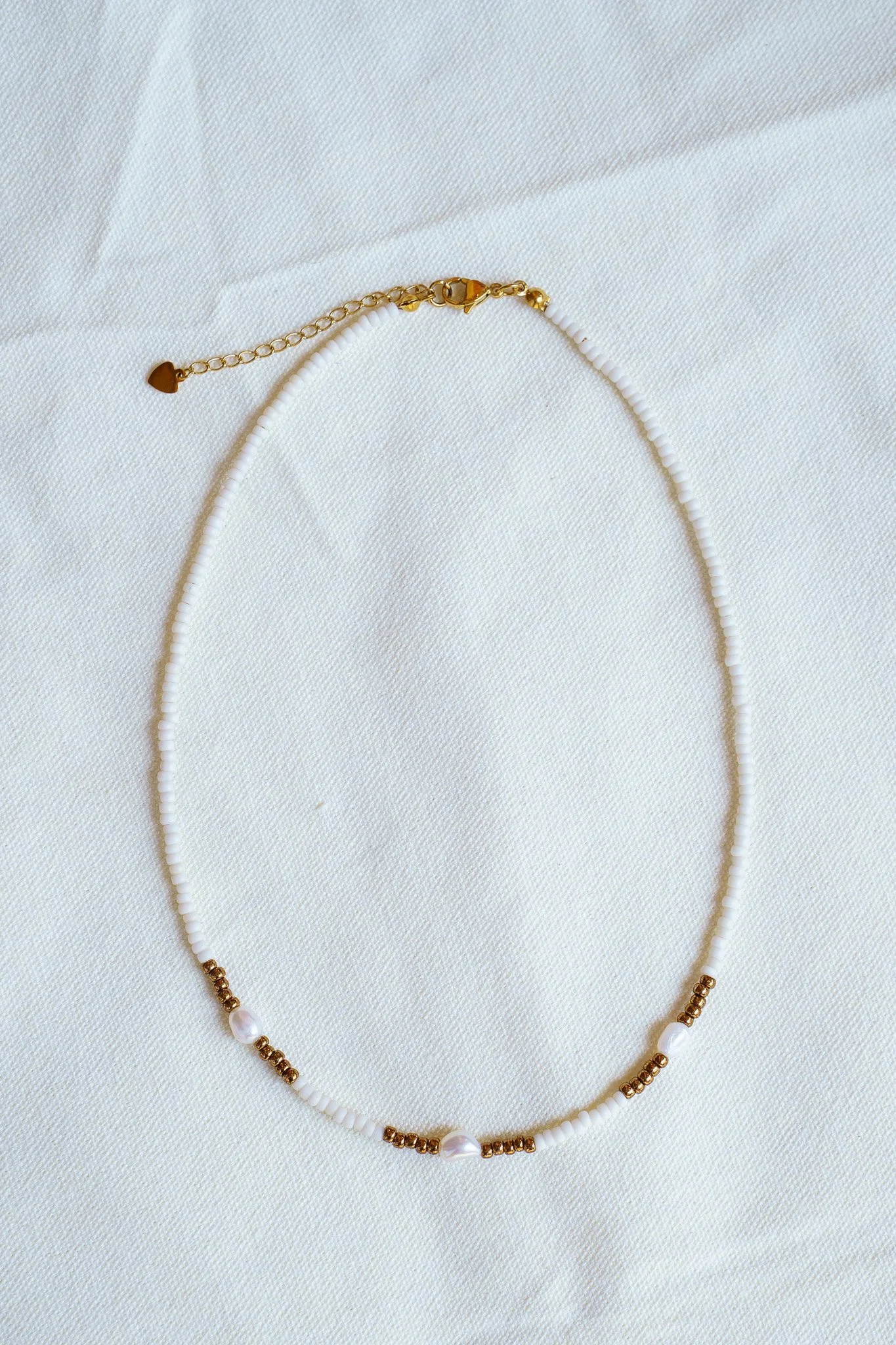 Handmade necklace with three white pearls and white and bronze seed beads with 18k gold PVD findings. Necklace measures approximately 16" with a 2" extender.
