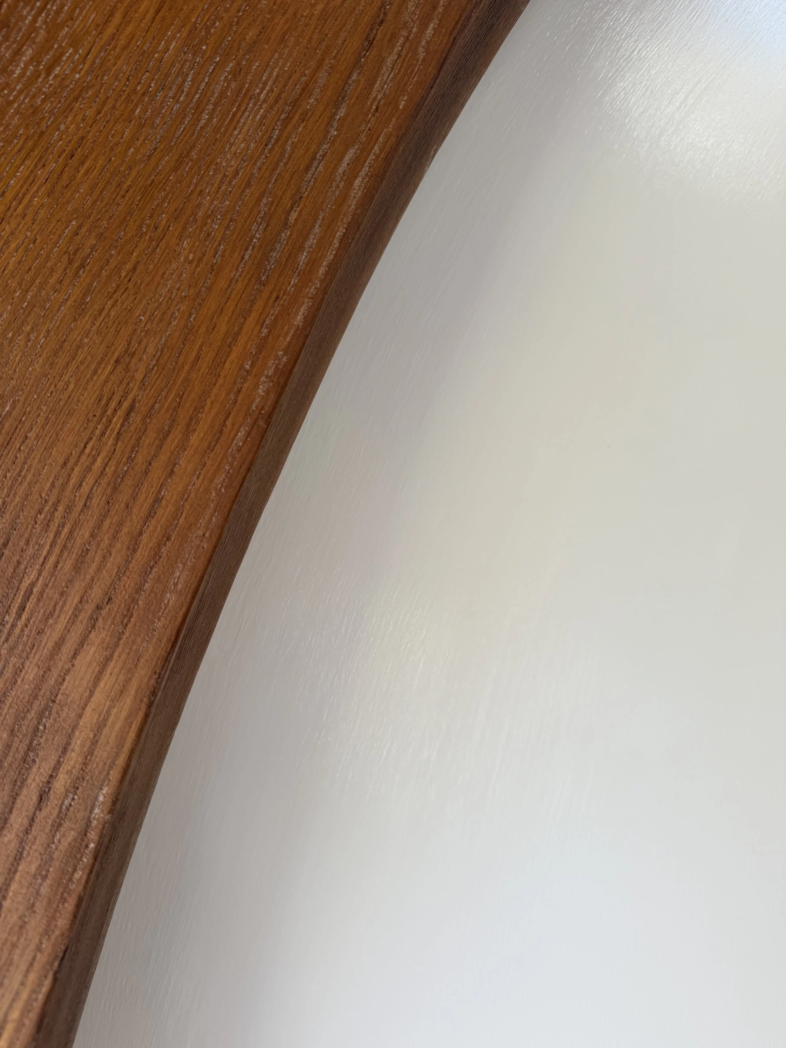 Close-up of a wooden edge against a white textured surface.