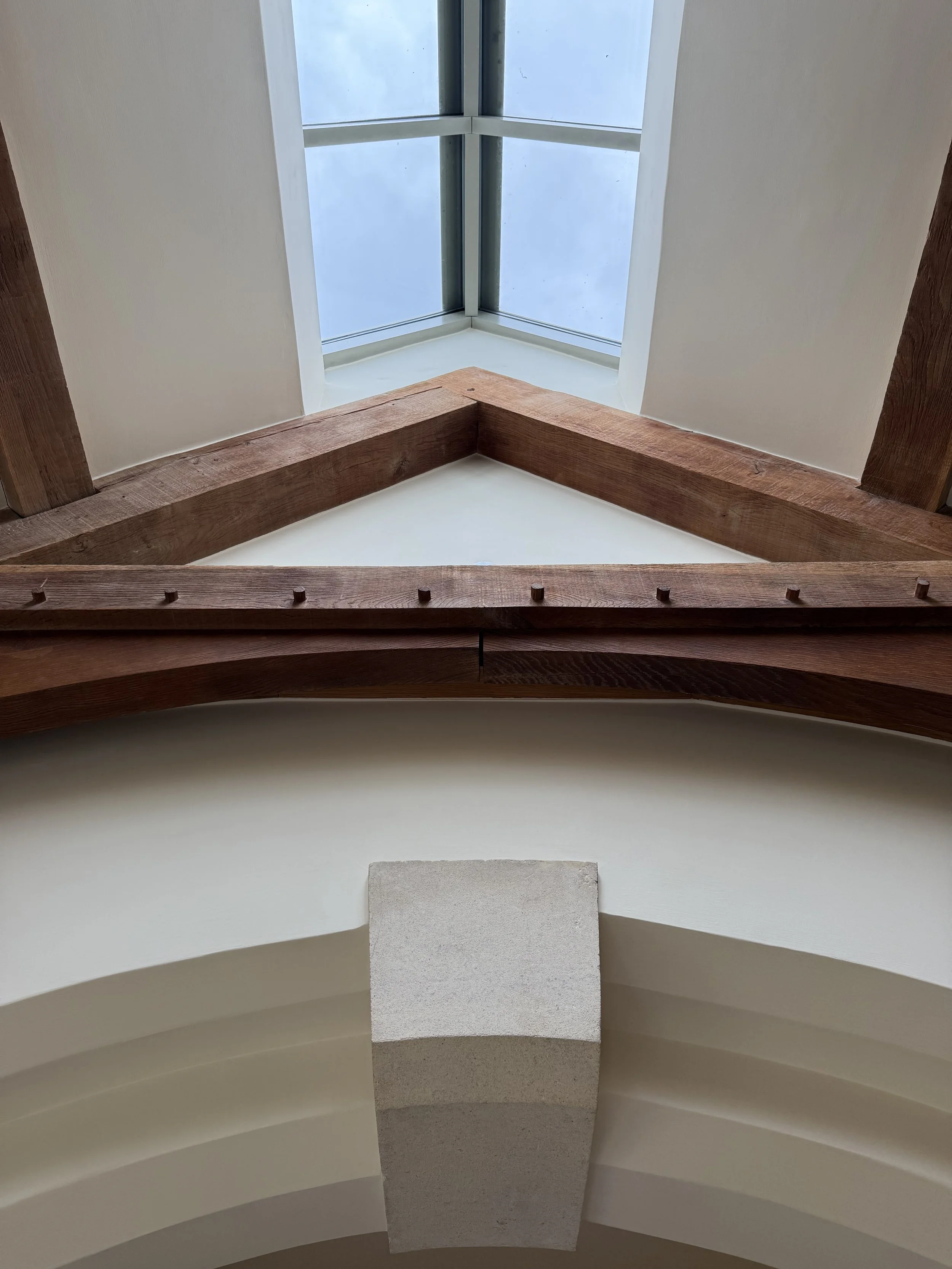 Looking up at a ceiling with a large skylight and wooden beams.