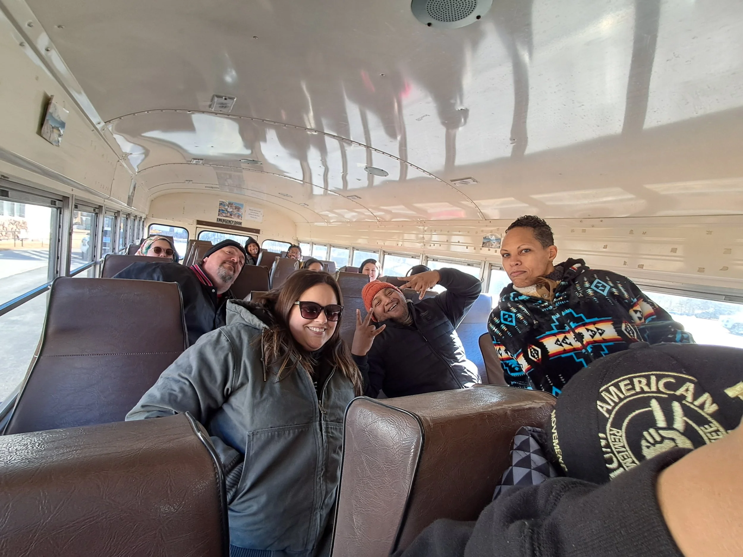 A group of people sitting on a bus, smiling and posing for the camera.