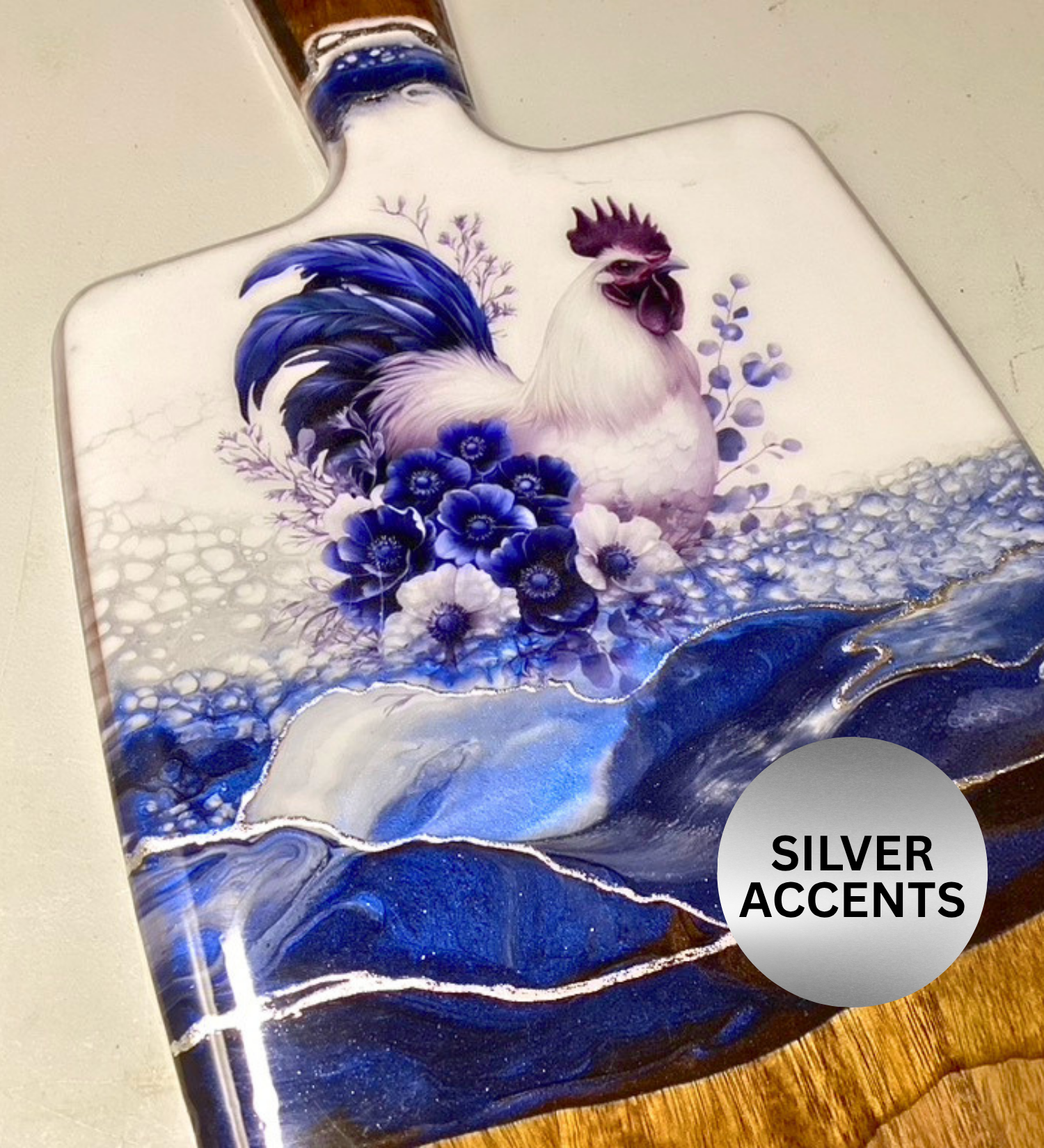 Handmade farmhouse charcuterie board with blue rooster artwork and flowing blue resin accents on natural hardwood.