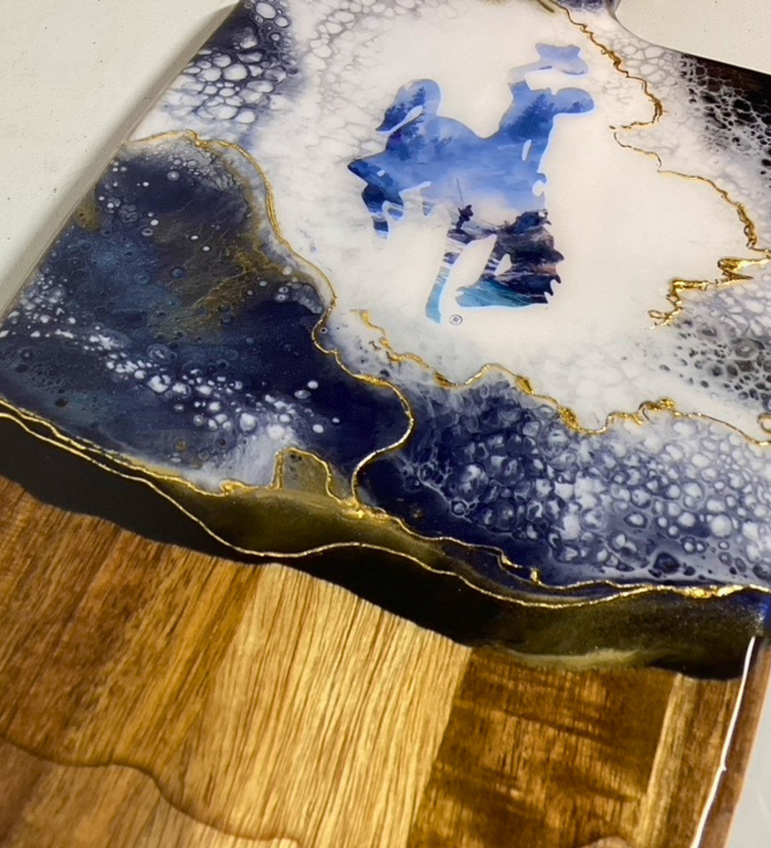 Handmade Wyoming charcuterie board with fly fisherman scene, resin art, and 24K gold accents on acacia wood