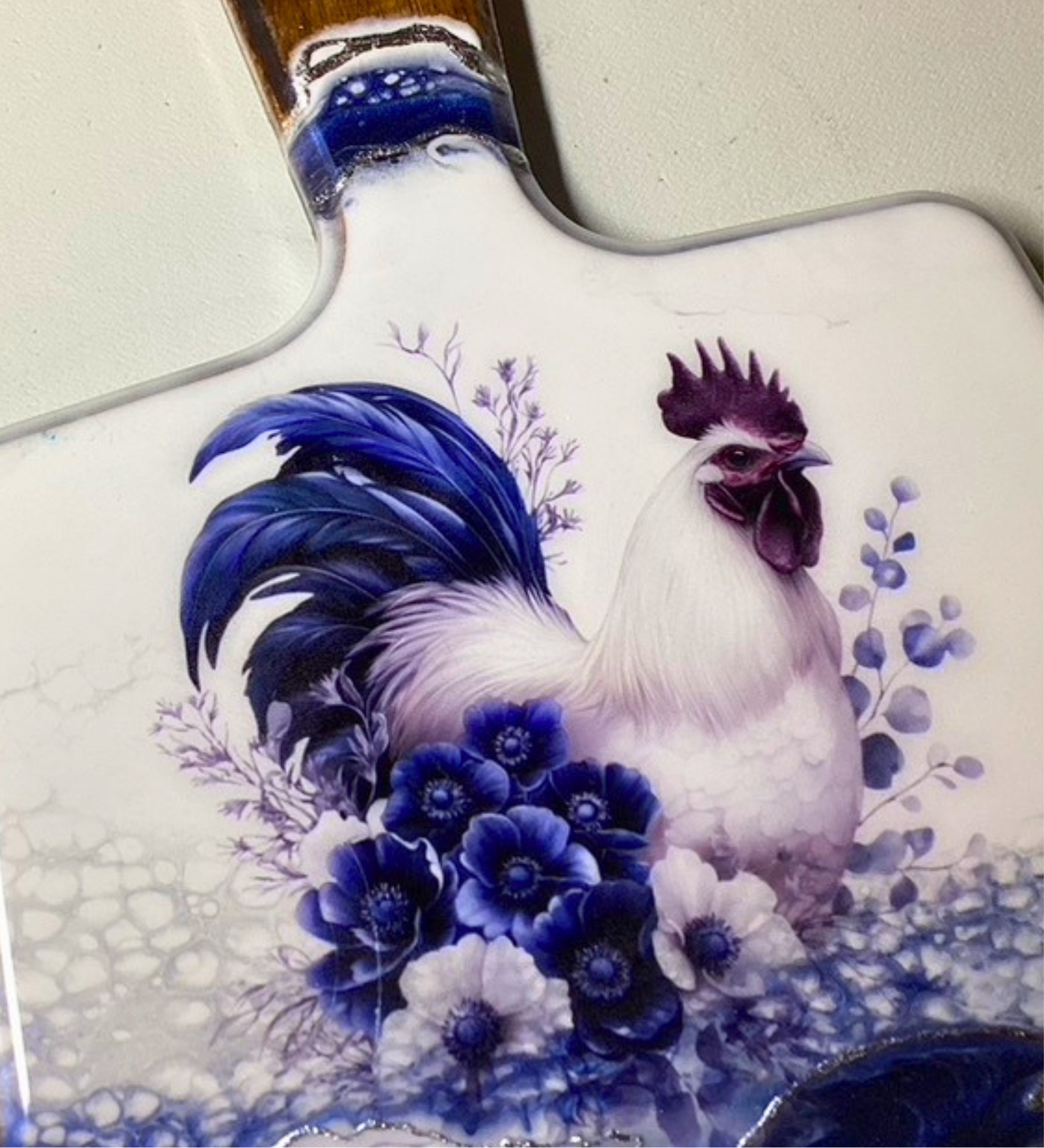 Handmade farmhouse charcuterie board with blue rooster artwork and flowing blue resin accents on natural hardwood.