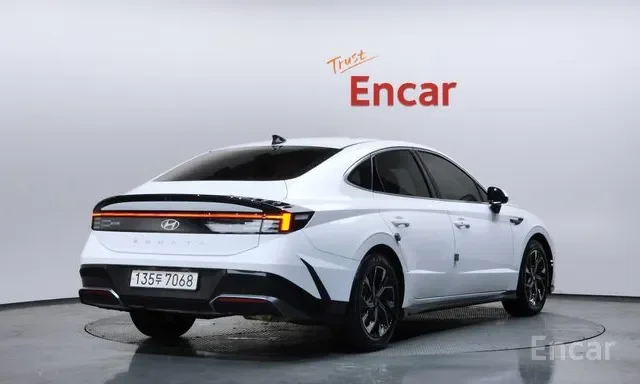 Front and side view of a white Hyundai electric sedan in a showroom with 'Trust Encar' sign on the wall.