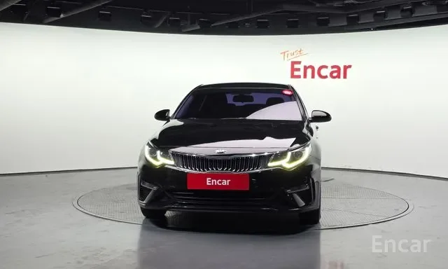 Black sedan car displayed in a showroom with Encar branding on a red sign in front and on the wall.