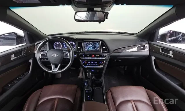 Inside view of a modern car interior featuring a dashboard, steering wheel, central touchscreen display, gear shift, and front seats with leather upholstery.