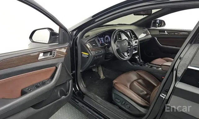 Interior of a black car showing the driver's seat, steering wheel, dashboard, and part of the passenger seat with brown leather upholstery.