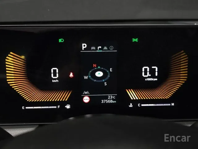 Digital car dashboard displaying vehicle in park, speed at 0 km/h, engine running at 0.7 x 1000 RPM, temperature 23°C, total distance 37,568 km, and various indicators including lane assist, lights, and seatbelt.