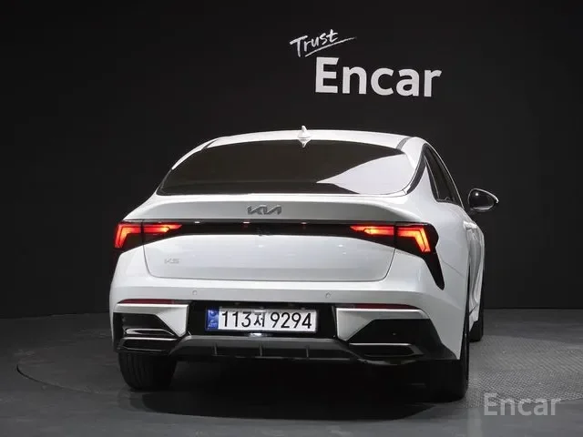 White Kia EV6 electric car parked indoors with a black background, Kia logo visible, and a license plate reading 113 X 9294. The words "Trust" and "Encar" are written on the wall behind the car.