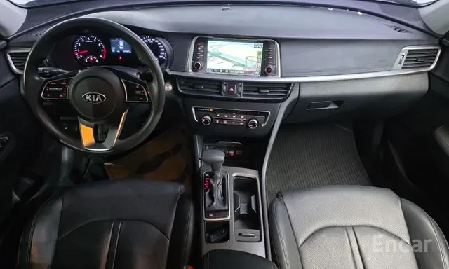 Interior of a Kia vehicle showing the steering wheel, dashboard, gear shifter, and center console with an infotainment screen.