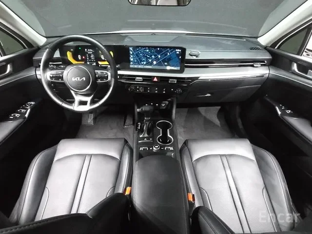 Interior of a modern Kia vehicle from the front seats, showing the dashboard, steering wheel, touchscreen display, and center console.