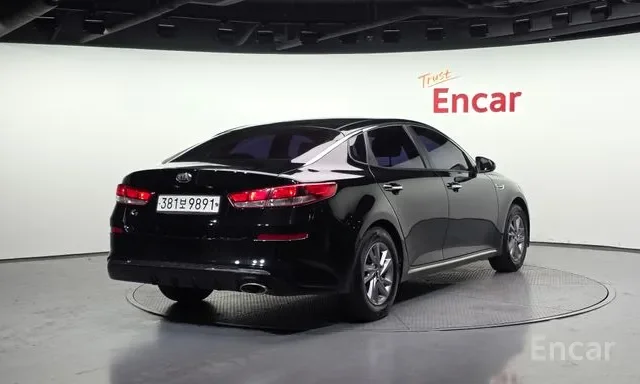 Black sedan car displayed on a rotating platform in a showroom, with white background and 'Trust Encar' signage.