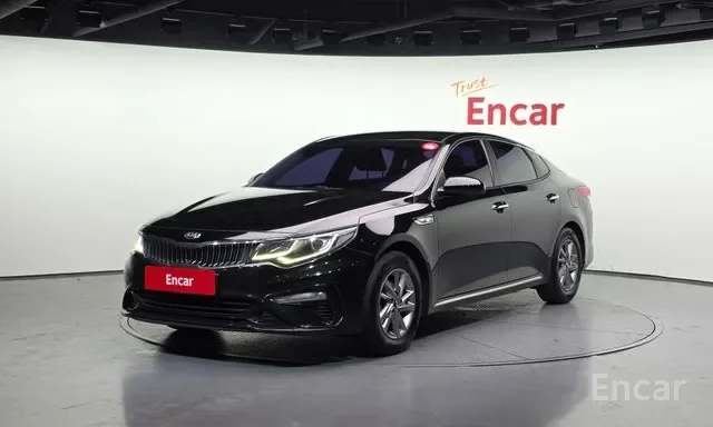 Black sedan displayed on a circular platform in a showroom with white walls and red 'Encar' branding.
