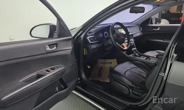 Interior of a black car showing the driver's side door open, with the dashboard, steering wheel, and front seat visible.