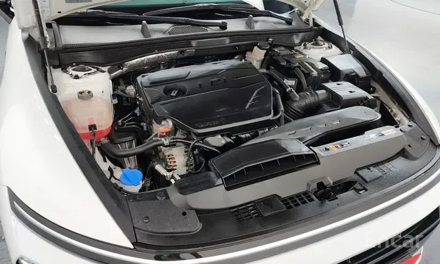 Under the open hood of a car, showing the engine and various engine components such as the coolant reservoir, air filter, and battery.