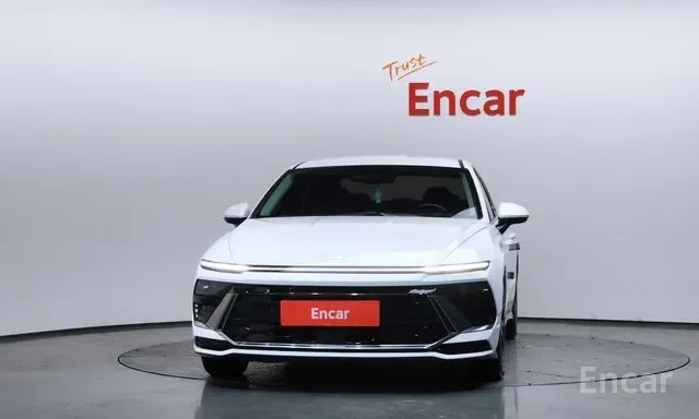 White sedan car in a showroom with 'Trust Encar' text on the wall behind it